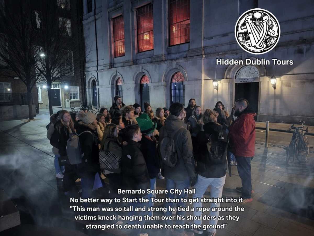 Tour group gathered at night outside Dublin city hall with a tour guide.